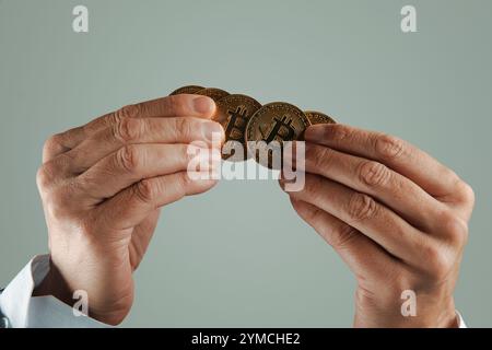 gros plan d'un homme d'affaires avec quelques bitcoins dans ses mains sur un fond gris pâle Banque D'Images