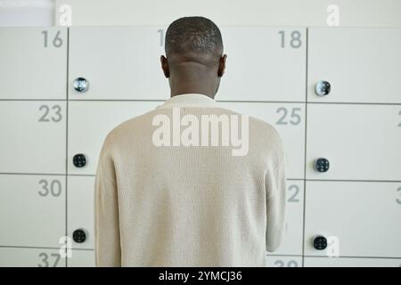 Main de travailleur de bureau afro-américain entrant le code sur le clavier numérique du casier intelligent stockant les effets personnels dans le coworking contemporain, COP Banque D'Images