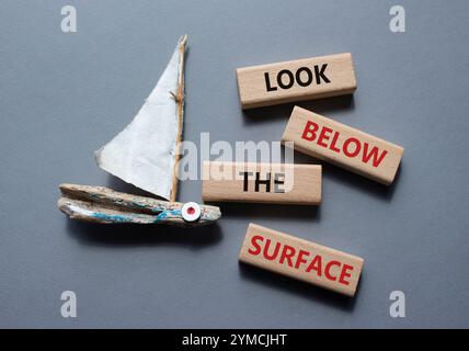 Regardez sous le symbole de surface. Mot concept regardez sous la surface sur des blocs de bois. Beau fond gris avec bateau. Business et regardez ci-dessous Banque D'Images