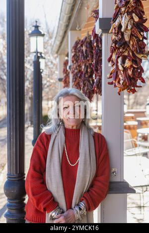 Portrait d'une femme souriante appuyée contre la colonne au café trottoir Banque D'Images