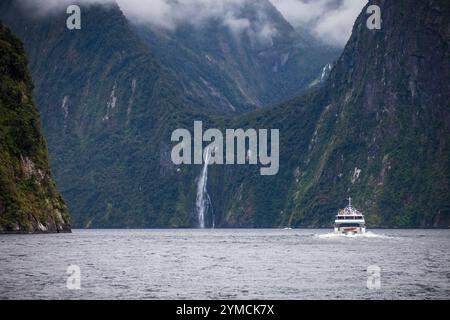 Ferry sur le fjord entouré de montagnes dans le parc national de Fiordland Banque D'Images