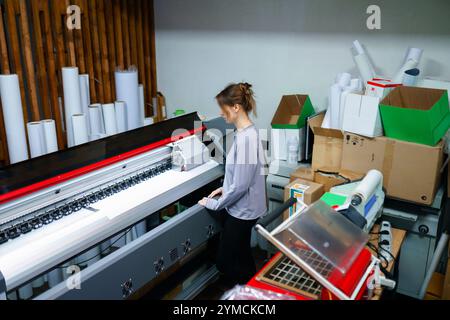 Femme opérant la machine dans le studio d'impression Banque D'Images