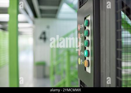 Vue latérale du panneau de numéro avec des boutons colorés pour appeler l'ascenseur reliant les étages d'entrepôt, espace de copie Banque D'Images