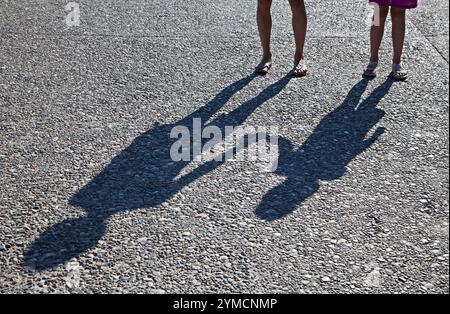 Deux personnes et leurs ombres marchent dans Cobblestone Street Banque D'Images