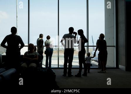 Touristes, voyageurs, silhouettes de gens dans la salle d'attente moderne de l'aéroport. Contre-jour, des gens méconnaissables Banque D'Images