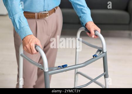 Homme senior utilisant le cadre de marche à la maison, gros plan Banque D'Images