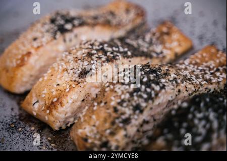 Tranches de saumon grillé avec sésame, assaisonnement et herbes sur papier parchemin pour la cuisson Banque D'Images