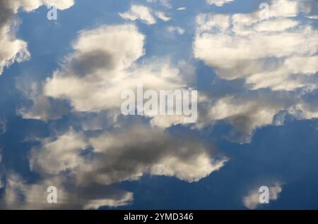 Reflet du ciel dans l'eau. Les nuages blancs comme la neige se reflètent dans l'eau bleue. Banque D'Images