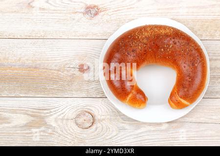 Pain fraîchement cuit et chaud en forme de croissant placé sur une surface de table en bois rustique Banque D'Images