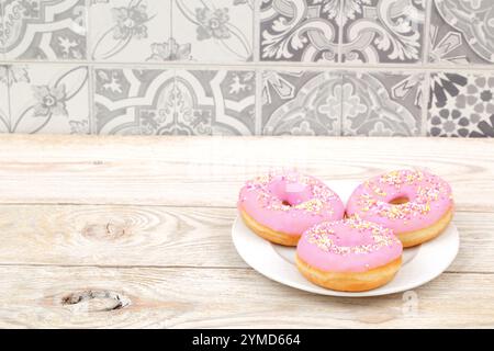 Dégustez de délicieux beignets givrés roses colorés superbement disposés sur une assiette Banque D'Images