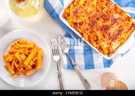 Pâtes Ziti cuites au four avec sauce tomate bolognaise ou marinara et fromage, dans une poêle et une assiette cuites, sur un espace de copie de table de cuisine blanc Banque D'Images