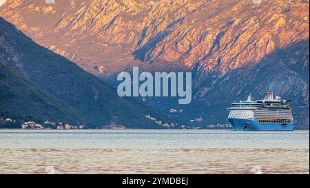 Kotor, Monténégro - 21 septembre 2024 : un navire de croisière Voyager of the Sea glisse dans les eaux calmes de la baie de Kotor au Monténégro à l'aube, avec mountai Banque D'Images