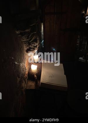 Un livre est placé sur une table avec deux bougies allumées. Les bougies sont régulièrement espacées et le livre est ouvert à une page. La pièce est faiblement éclairée, créant un confortable. Lettonie, Riga 08.10.2023Atmosphere Banque D'Images