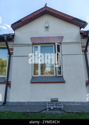 Un bâtiment traditionnel avec des accents rouges et un grand toit en pente, encadré par des arbres par une journée ensoleillée. L'architecture reflète l'élégance du classique Banque D'Images
