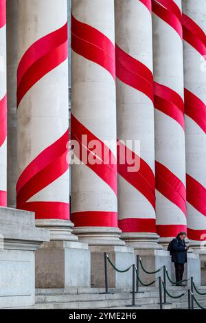 Londres, Royaume-Uni. 21 novembre 2024. Les colonnes à l'extérieur de la Royal Exchange à côté de la Banque d'Angleterre ont été ornées de rubans rouges pour donner l'impression de cannes géantes de bonbons de Noël. C'est la première fois que de telles décorations de Noël sont en place sur le bâtiment, apportant des couleurs attrayantes à la City de Londres. Credit : Stephen Chung / Alamy Live News Banque D'Images