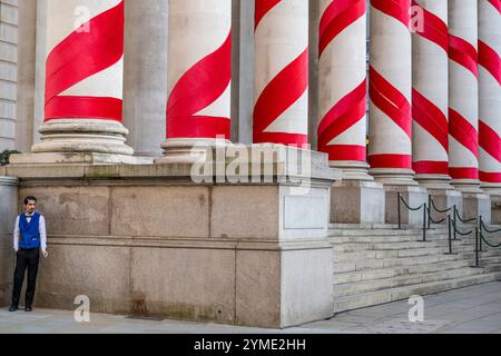 Londres, Royaume-Uni. 21 novembre 2024. Les colonnes à l'extérieur de la Royal Exchange à côté de la Banque d'Angleterre ont été ornées de rubans rouges pour donner l'impression de cannes géantes de bonbons de Noël. C'est la première fois que de telles décorations de Noël sont en place sur le bâtiment, apportant des couleurs attrayantes à la City de Londres. Credit : Stephen Chung / Alamy Live News Banque D'Images