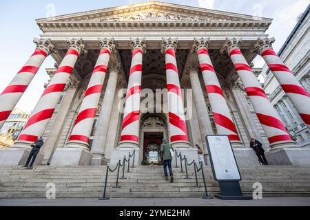 Londres, Royaume-Uni. 21 novembre 2024. Les colonnes à l'extérieur de la Royal Exchange à côté de la Banque d'Angleterre ont été ornées de rubans rouges pour donner l'impression de cannes géantes de bonbons de Noël. C'est la première fois que de telles décorations de Noël sont en place sur le bâtiment, apportant des couleurs attrayantes à la City de Londres. Credit : Stephen Chung / Alamy Live News Banque D'Images