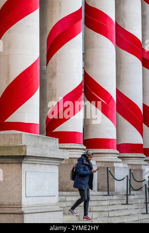 Londres, Royaume-Uni. 21 novembre 2024. Les colonnes à l'extérieur de la Royal Exchange à côté de la Banque d'Angleterre ont été ornées de rubans rouges pour donner l'impression de cannes géantes de bonbons de Noël. C'est la première fois que de telles décorations de Noël sont en place sur le bâtiment, apportant des couleurs attrayantes à la City de Londres. Credit : Stephen Chung / Alamy Live News Banque D'Images