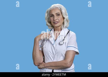 Portrait de joli médecin féminin senior souriant avec stéthoscope sur fond bleu. Lady Doctor regardant la caméra et souriant Banque D'Images