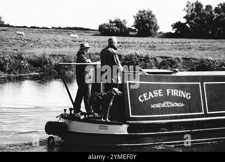 CAMBRIDGESHIRE, Royaume-Uni - 18 AOÛT 2017 : couple avec chien voyageant sur un bateau étroit traditionnel le long de la rivière Great Ouse. Les vacances nautiques sont très populaires Banque D'Images