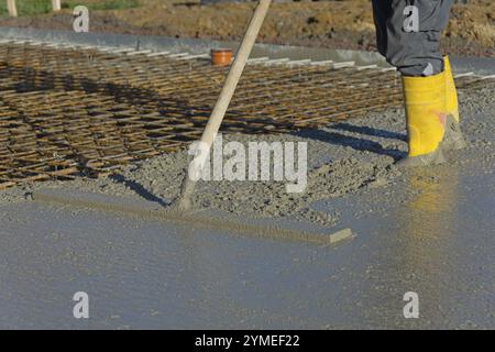 Ouvrier de construction lissant le béton sur une dalle de sol Banque D'Images