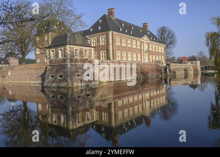 Château historique avec douves avec reflet dans l'eau, entouré d'arbres et ciel clair, ahaus, muensterland, allemagne Banque D'Images