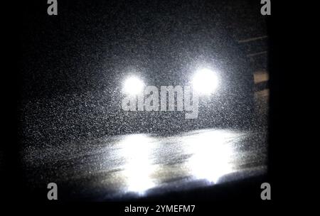 21 novembre 2024, Bavière, Münsing : une voiture roule sur une route dans la neige. Le Service météorologique allemand (DWD) a émis un avertissement de mauvais temps pour de fortes chutes de neige dans certaines parties de la Bavière. Photo : Sven Hoppe/dpa Banque D'Images