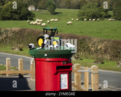 Bombe de fil couvrant la boîte aux lettres rouge gros plan (affichage de scène de ferme, art de rue décoratif de bombardement de fil) - Bolton Abbey village, North Yorkshire, Angleterre Royaume-Uni. Banque D'Images