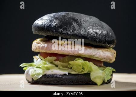 Hamburger avec pain noir. Hamburger sur fond sombre Banque D'Images
