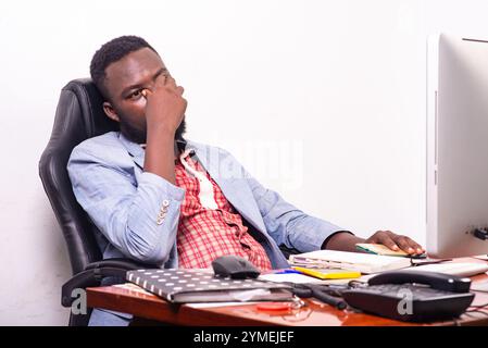 homme d'affaires en veste assis au bureau devant l'ordinateur à l'air épuisé. Banque D'Images