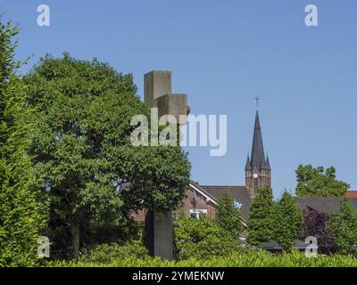 Tour de l'église s'élève au-dessus des toits et des arbres, ciel ensoleillé en arrière-plan, weseke, muensterland, allemagne Banque D'Images