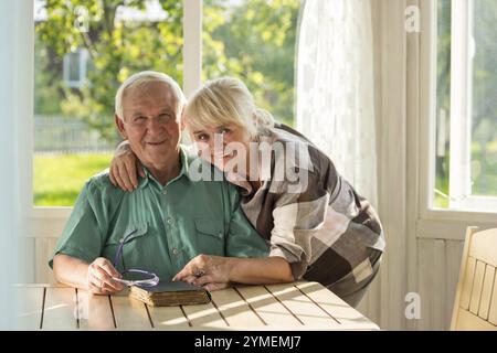 Couple senior avec un livre. Homme et femme souriant à l'intérieur. Deux vies, une histoire Banque D'Images