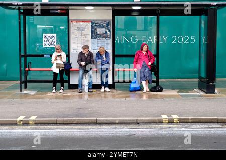 Attente dans un abri d'arrêt de bus un jour de pluie devant un grand site de réaménagement immobilier sur Oxford Street, Londres. Banque D'Images