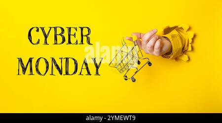 Main tenant un panier avec les mots Cyber Monday écrits en dessous. L'image a une ambiance ludique et légère, car c'est une façon créative de le faire Banque D'Images