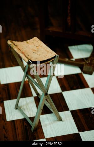 Palette de peinture d'artiste aux couleurs vives, reposant sur un chevalet, posée sur un sol à carreaux noir et blanc, avec chaise d'artiste Banque D'Images