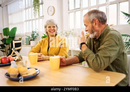 Couple senior appréciant le petit déjeuner et la conversation à la maison Banque D'Images