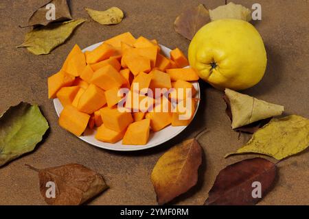 Image de fruits de coing, plats avec une gourde coupée entourée de feuilles de bois tombées. Cydonia oblonga. Banque D'Images