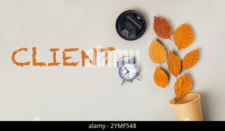 Horloge et une tasse sont placées sur une table avec le mot client écrit au milieu. Concept de professionnalisme et de ponctualité Banque D'Images