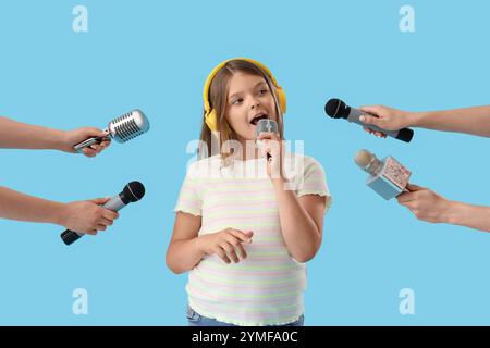 Petite fille mignonne avec différents microphones chantant sur fond bleu Banque D'Images