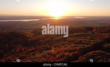 Une superbe scène de forêt automnale avec un feuillage rouge, orange et jaune éclatant. Le soleil couchant jette une lueur chaude sur la vallée ci-dessous. Parfait pour natu Banque D'Images