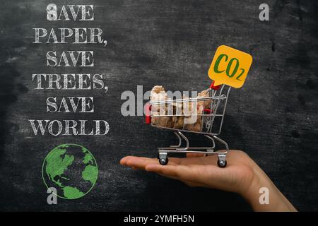 Main tenant un panier avec un panneau qui dit Save Paper, Save Trees, Save CO2, Save World Banque D'Images