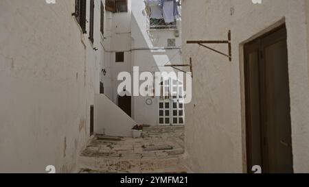 Pittoresque ruelle étroite avec des bâtiments blanchis à la chaux à ostuni, dans les pouilles, en italie, avec une rue ensoleillée, une buanderie suspendue et un archi italien authentique Banque D'Images