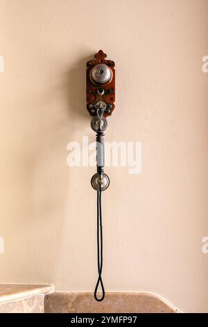 Téléphone ancien avec combiné et cloche accroché dans une pièce sur un mur de couleur rose. Banque D'Images