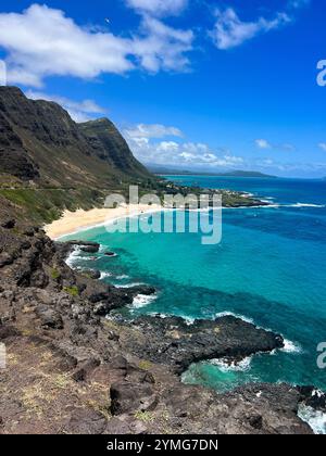 Une vue imprenable depuis une falaise surplombant une crique isolée avec une plage de sable et une eau turquoise cristalline. Les gens apprécient la plage Banque D'Images