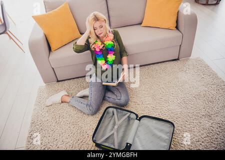 Photo de femme déprimée stressée assise sur le sol se préparant pour un futur voyage de week-end organisant valise à l'intérieur de l'appartement Banque D'Images