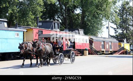 Excursion buggy dessiné par un couple de chevaux, vieux cabooses colorés en arrière-plan, dans le pays Amish près de Strasburg, dans le comté de Lancaster, PA Banque D'Images