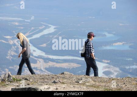 Deux personnes sur le sommet de la montagne regardent au-dessus de la vue lointaine de la vallée de la rivière et des lacs à Jasper Canada - couple concept se séparant Banque D'Images
