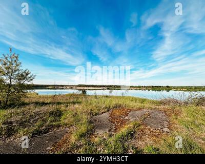 Beau ciel bleu avec quelques nuages et un lac en arrière-plan. Le ciel est dégagé et le lac calme Banque D'Images