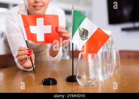 Fille méconnaissable pose des drapeaux midget du Mexique et de la Suisse avant les négociations internationales Banque D'Images