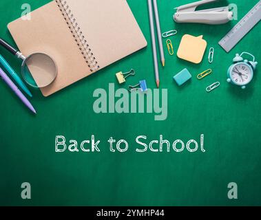 Cahier vert avec une loupe et une horloge sur le dessus. Le cahier est intitulé retour à l'école Banque D'Images